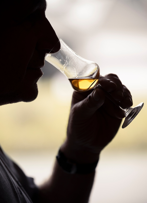 Logez Distillerie Zimmerli Mann riecht an einem Stielglas, das ein in Eigenproduktion alkoholisches Getränk enthält