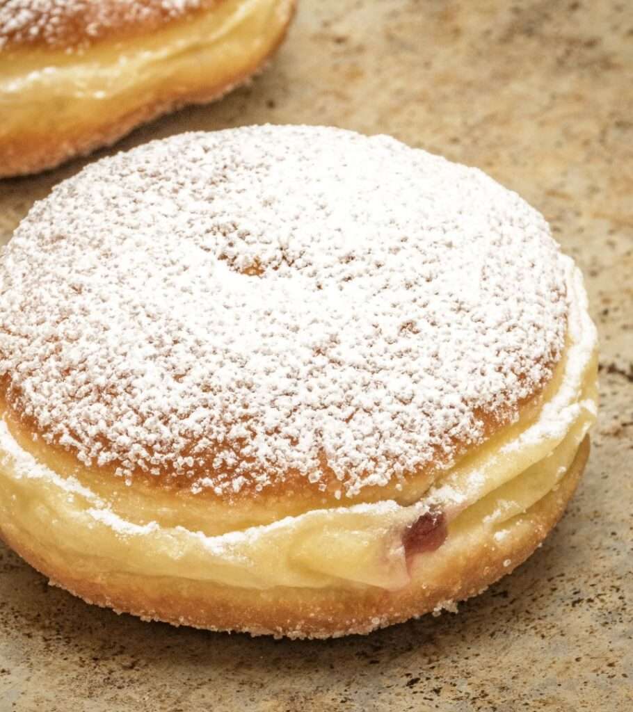 Mit Puderzucker bestreifter Berliner mit Vanillecremefüllung