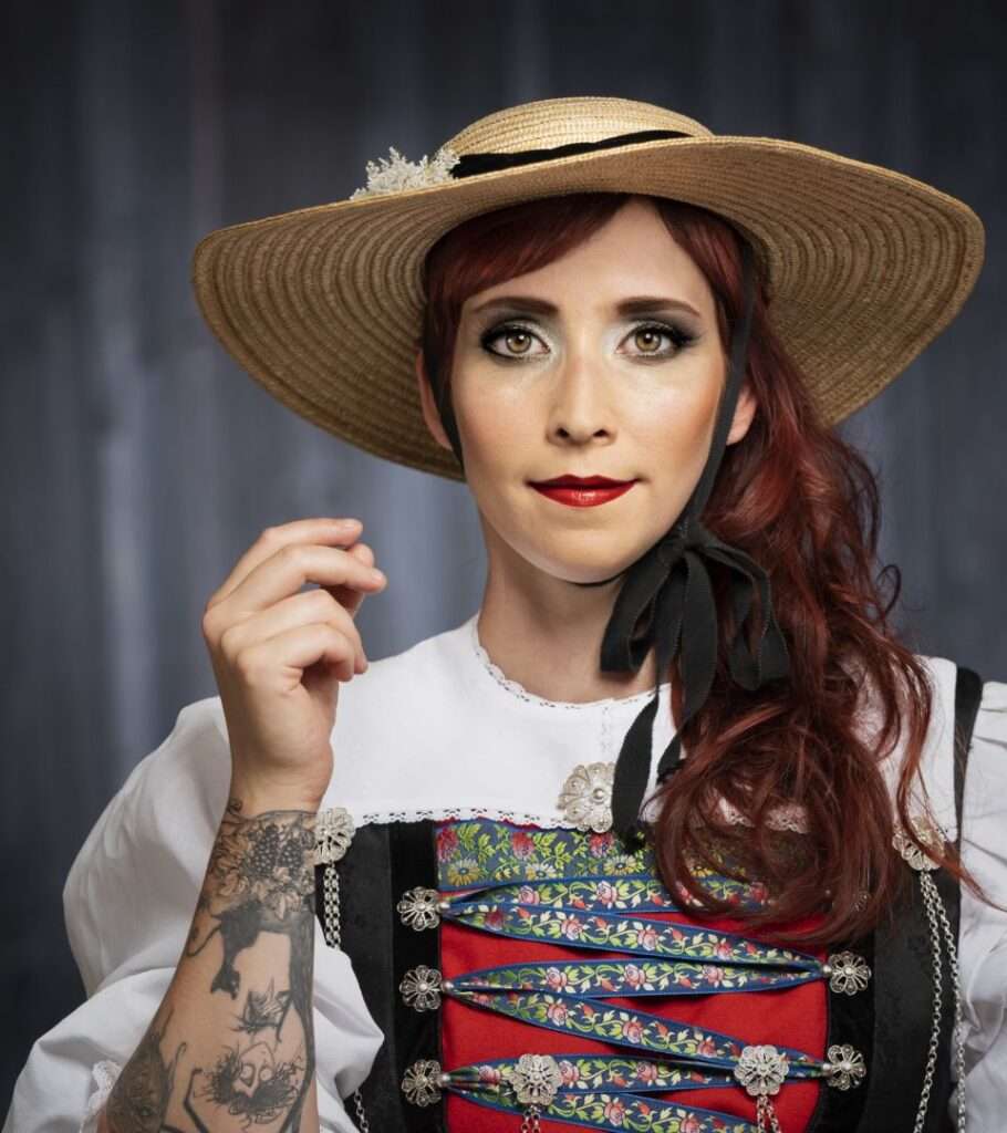 Porträt einer Frau in traditioneller Tracht mit Strohhut und rotem Oberteil