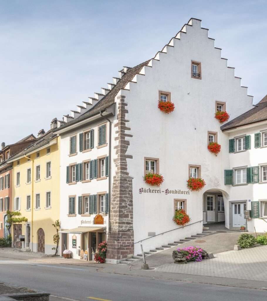 Bäckerei Häfeli: historische Häuserzeile mit Bäckerei und Konditorei, weißes Giebelhaus mit Blumen an den Fenstern