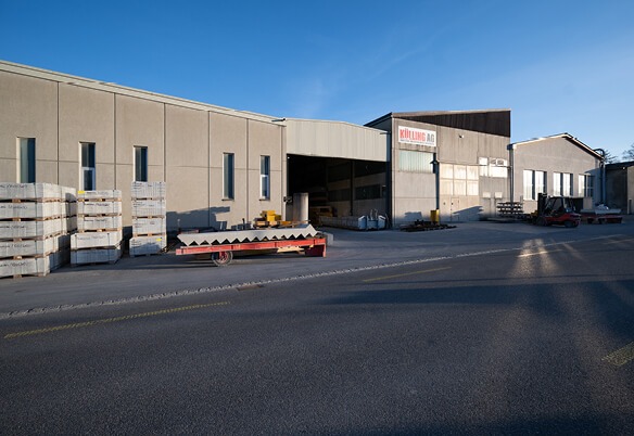 Industriehalle mit Lagerbereich und gestapelten Paletten vor dem Gebäude