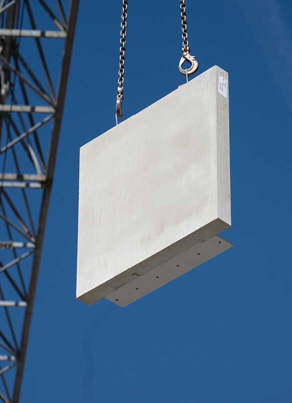 Ein großer weißer Betonblock hängt an Ketten vor blauem Himmel