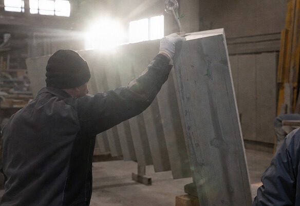 Arbeiter hebt eine große Betonplatte in einer Werkhalle an